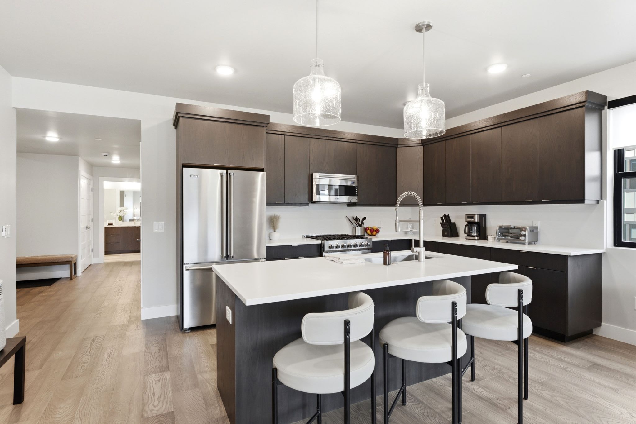A modern kitchen with a central island, stainless steel appliances, and pendant lighting.