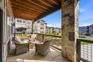 A covered outdoor seating area with wicker furniture and a stone pillar. - Family Friendly 3 Bedroom Condo Near Deer Valley East Village (Heber City)