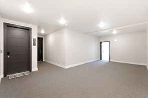 A spacious, empty room with a carpeted floor, white walls, and a dark door. - Family Friendly 3 Bedroom Condo Near Deer Valley East Village (Heber City)