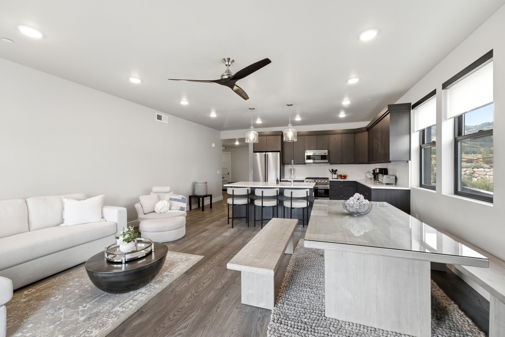 Una cocina moderna con una isla central, comedor y una zona de estar con sofá y sillones.