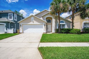 A residential street with houses, a driveway, and a well-maintained lawn. - Luxury 5BD home close to Disney with Private Pool (Kissimmee)