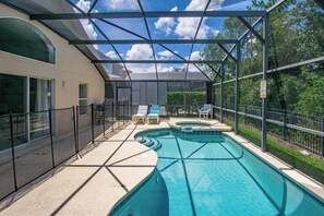 A swimming pool with a sunshade structure, lounge chairs, and a fenced patio area. - Luxury 5BD home close to Disney with Private Pool (Kissimmee)
