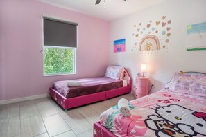 Ein zartrosa Schlafzimmer mit zwei Betten, einem Fenster und Wanddekorationen.