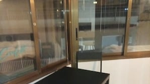 Una stanza con un tavolo e due sedie, una finestra con persiane e vista su un edificio.