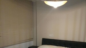 Una camera da letto con un letto, un comodino, una lampada e una finestra con persiane.