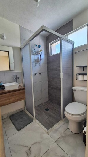 Un bany modern amb plat de dutxa, vàter i rentapans.