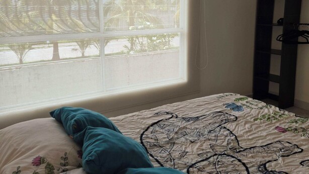 A bedroom with a bed, a window, and a black shelf. - Santa Ana el Dorado (San José Novillero)