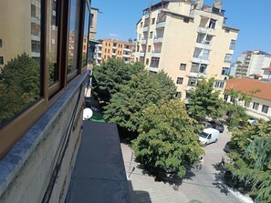 A residential area with multi-story buildings, trees, and parked cars.