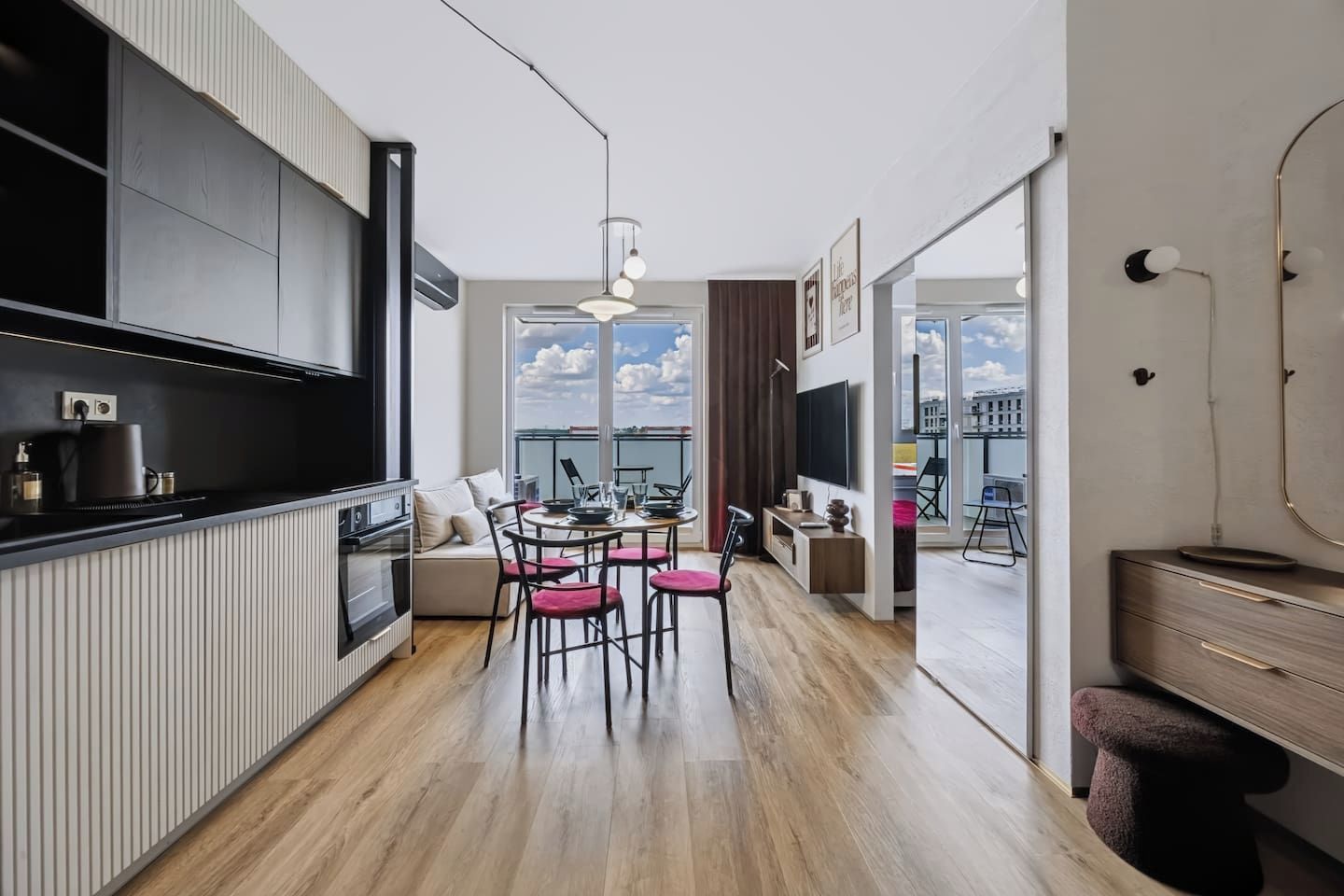 A modern kitchen with a dining area, large windows, and a view of the city.