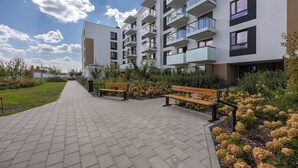 En modern hyresfastighet med en asfalterad gångväg, bänkar och anlagda grönområden.