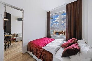 Un dormitorio moderno con una cama grande, vistas al mar a través de una ventana y un área de comedor con mesa y sillas.