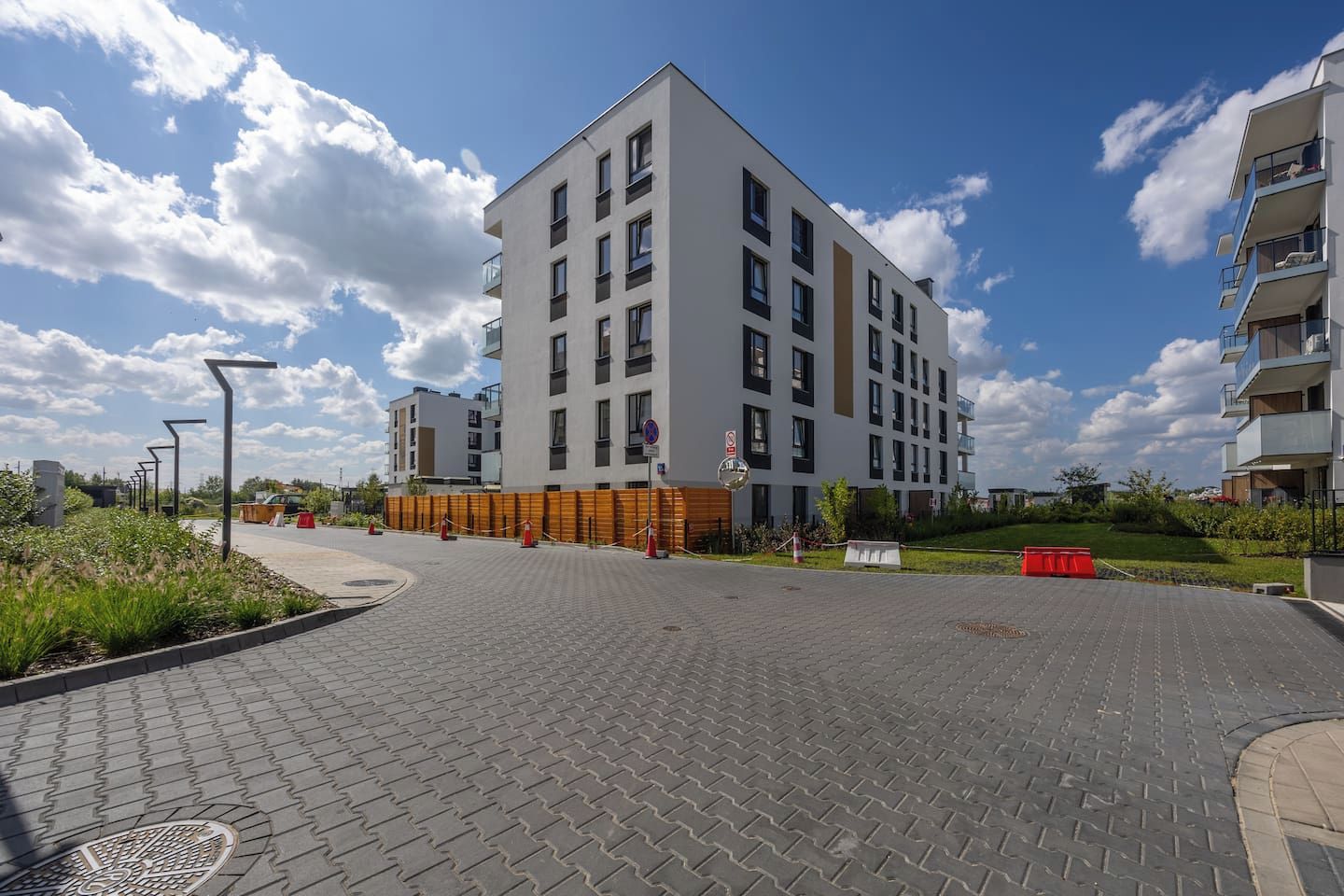 A modern multi-story building with a flat roof, a paved courtyard, and a clear sky.