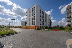 Ein modernes, mehrstöckiges Gebäude mit flachem Dach, einem gepflasterten Innenhof und blauem Himmel.