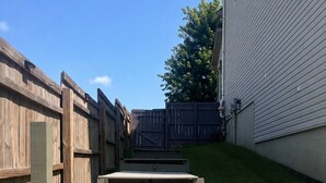 Une terrasse en bois mène à une maison à l’extérieur blanc.
