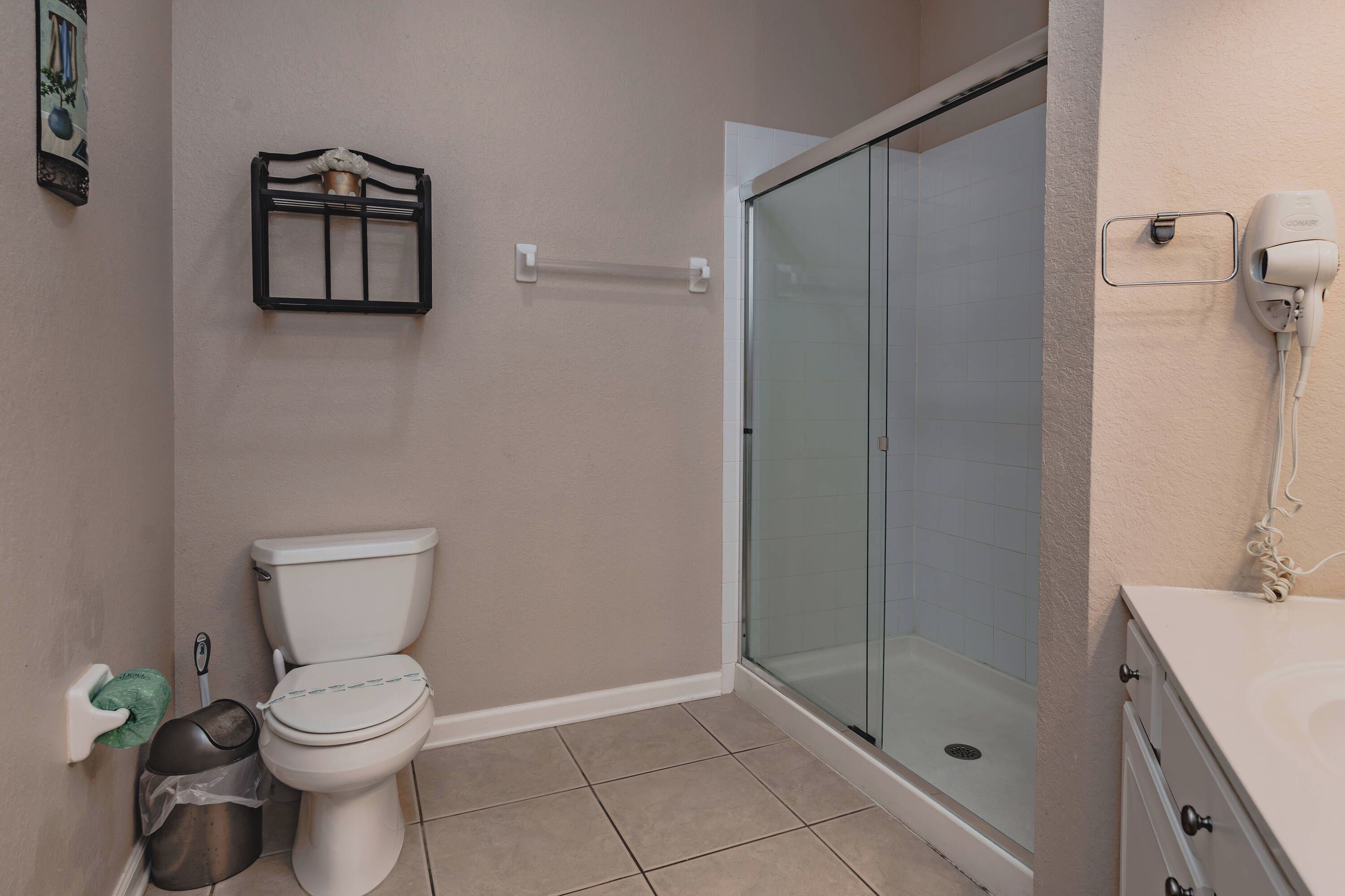 Een badkamer met een toilet, een douchecabine van glas en een handdroger aan de muur.