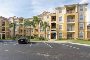 A multi-story residential building with a parking lot in front. - Comfortable 3BR Vista Cay Near Universal (Orlando)