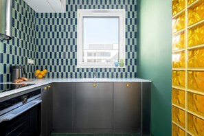 A kitchen with a window, a sink, and a countertop with a kettle and oranges. - Designer Apartment with Balcony | 1 Bedroom (Poznań)