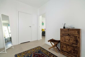 A room with a wooden dresser, a small stool, a patterned rug, and a mirror. - Designer Apartment with Balcony | 1 Bedroom (Poznań)