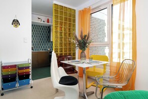 A dining area with a table, chairs, a vase with flowers, and a window with curtains. - Designer Apartment with Balcony | 1 Bedroom (Poznań)