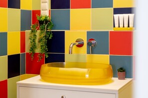 A bathroom with a yellow sink, a white cabinet, and a colorful tiled wall. - Designer Apartment with Balcony | 1 Bedroom (Poznań)