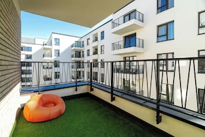 Ein Balkon mit grünem Kunstrasen und einem orangefarbenen Schwimmreifen.