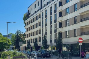 Ein mehrstöckiges Gebäude mit einer Reihe von Balkonen, einem Verbotsschild und abgestellten Autos.