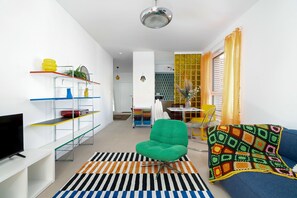 Ein modernes Wohnzimmer mit einem grünen Sessel, einer Couch, einem Flachbildfernseher und einem Streifenmuster-Teppich.