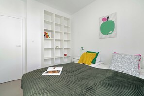 Ein Schlafzimmer mit einem Bett, einem weißen Kleiderschrank und einem Bücherregal.