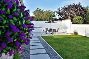 A patio with a table and chairs, a pathway, and a white wall. - Seven Glen: stylish coastal escape near the beach (Portrush)