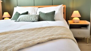 Un llit ben fet amb edredó blanc i una manta de punt beix.