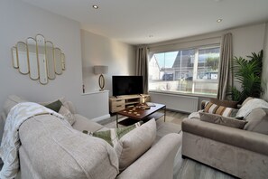 Ein modernes Wohnzimmer mit einer Couch, einem Couchtisch und einem Fernseher.