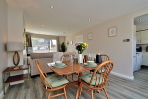 A dining area with a wooden table, four chairs, and a vase of flowers. - Seven Glen: stylish coastal escape near the beach (Portrush)