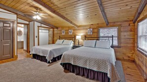 A cabin with two beds, wooden walls, a ceiling fan, and a window with blinds. - Log Cabin on 2 acres, hot tub, pond, fishing, pets, 1 mile TN Riverplace Venue (Chattanooga)