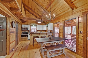 A wooden cabin interior with a kitchen, dining area, and large windows. - Log Cabin on 2 acres, hot tub, pond, fishing, pets, 1 mile TN Riverplace Venue (Chattanooga)