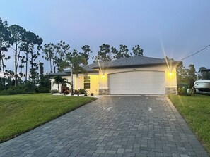 Une maison d’habitation avec un garage, une allée pavée et une pelouse.