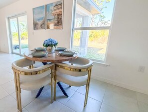 Ein Essbereich mit einem runden Tisch, vier Stühlen und einem Blumenstrauß.