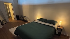 Ein Schlafzimmer mit einem Bett, zwei Nachttischlampen, einer Pendelleuchte, einer Tür und einem kleinen Tisch mit einer Lampe.