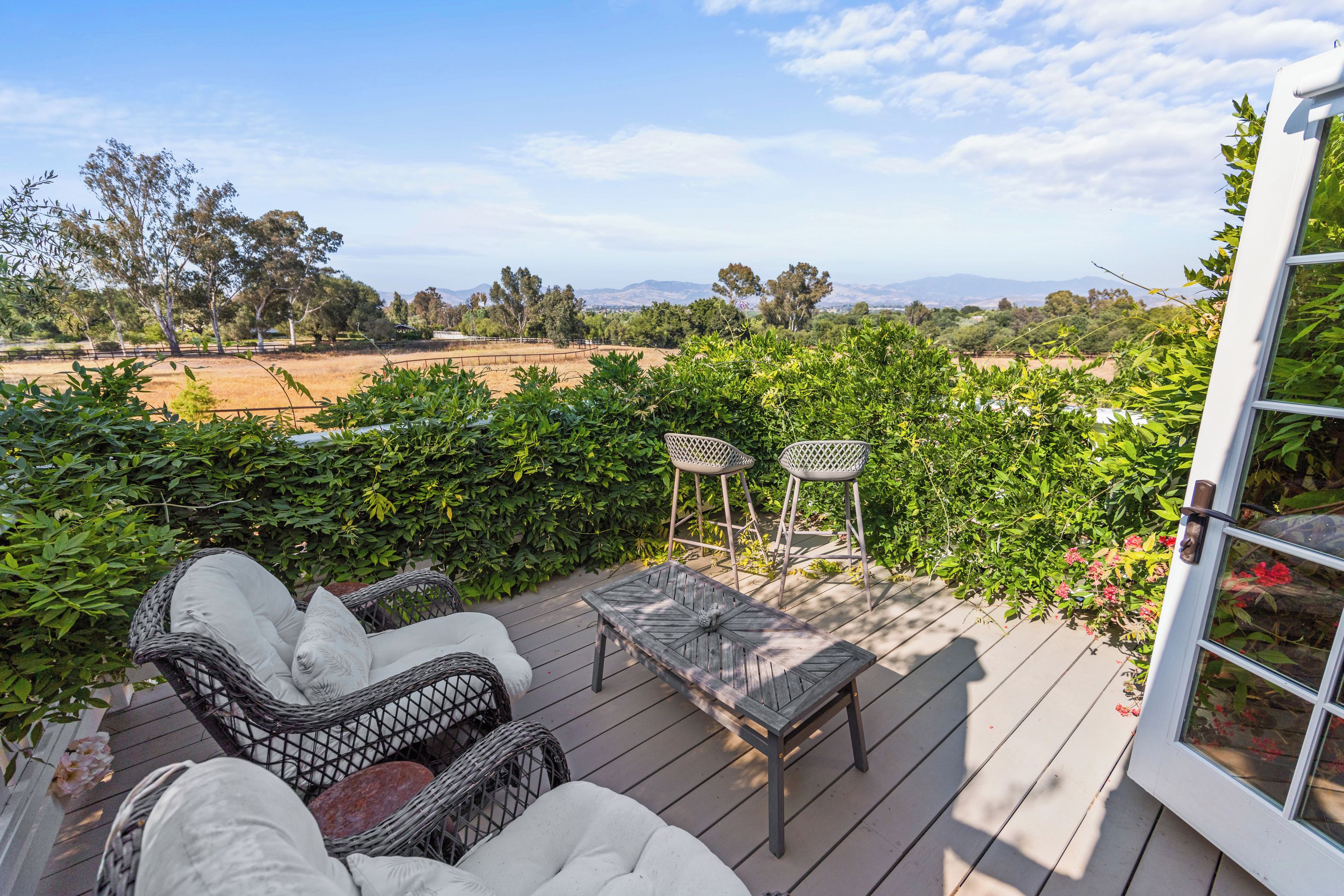 An outdoor patio with wicker furniture, a table, and chairs.