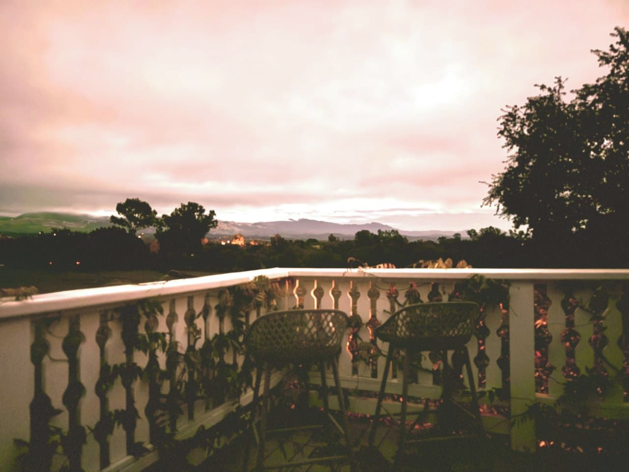 Un balcon avec une balustrade, deux chaises et une vue sur le paysage.
