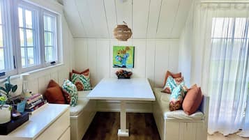 A cozy room with a white table, bench seating, and a painting above the table.