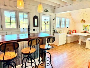 Una cocina con barra, taburetes de madera y lámparas colgantes.