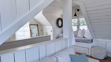 Een wit houten interieur met een hoogslaper, een witte bank en een bankje.