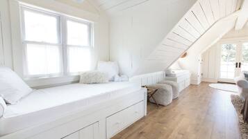 Una habitación con un banco empotrado junto a la ventana, un espacio para dormir elevado y suelo de madera.