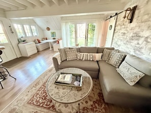 A living room with a sectional sofa, a coffee table, and a dining area with a bench.