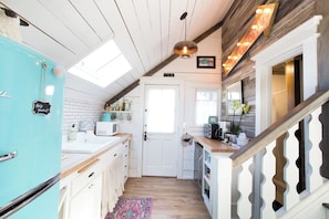A kitchen with a turquoise refrigerator, white cabinetry, a wooden ceiling, and a staircase with a white railing.