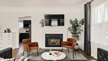A living room with a fireplace, two armchairs, a coffee table, and a sofa.
