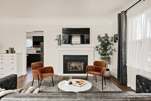 A living room with a fireplace, two armchairs, a coffee table, and a sofa.