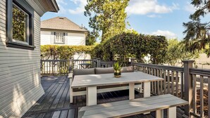 Una terrazza con tavolo e panche, circondata da una ringhiera in legno e vegetazione.