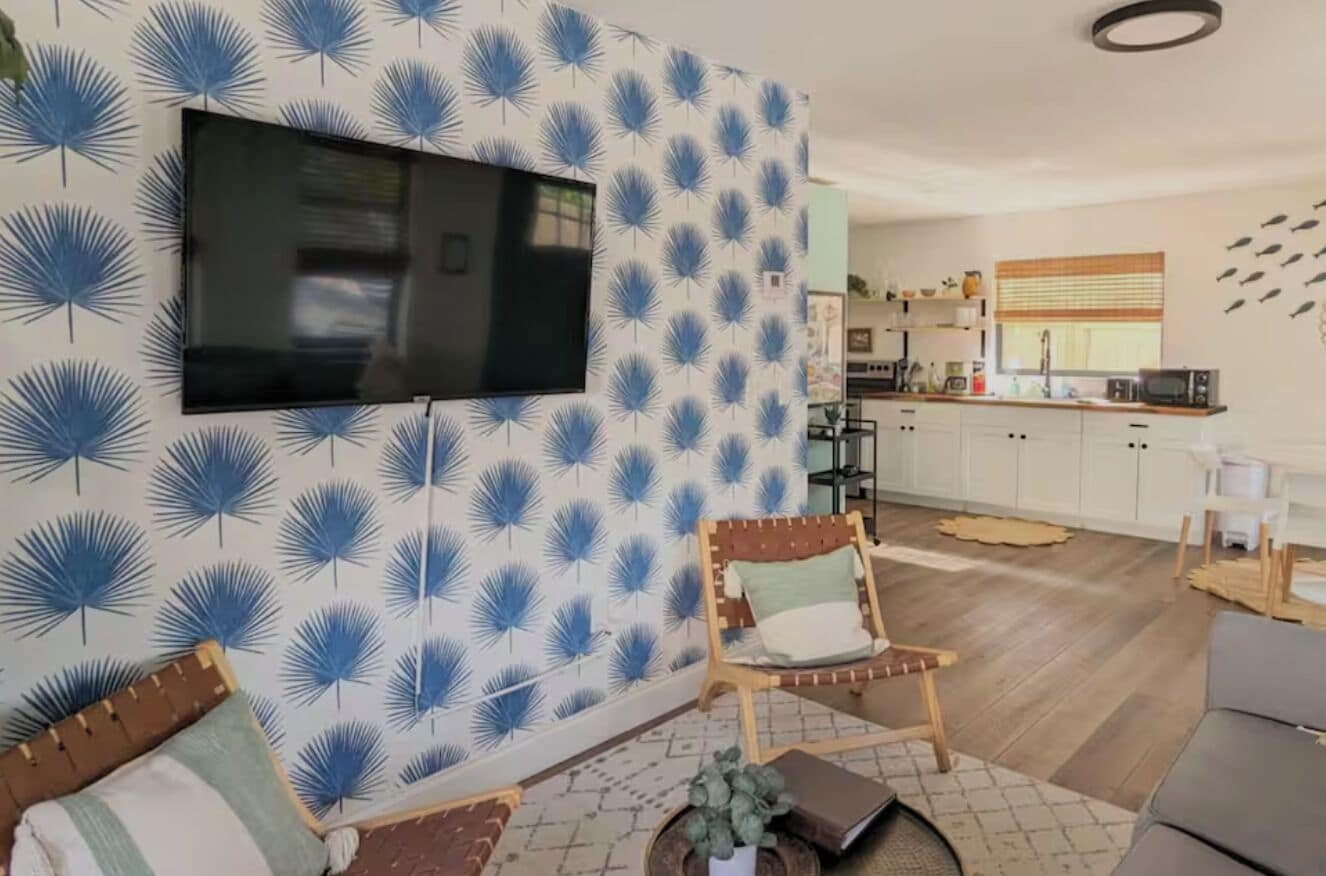 Ein Wohnzimmer mit Flachbildfernseher an der Wand, einer Couch und einem Couchtisch.