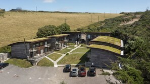 Un edificio moderno con techo plano y un estacionamiento con varios automóviles.